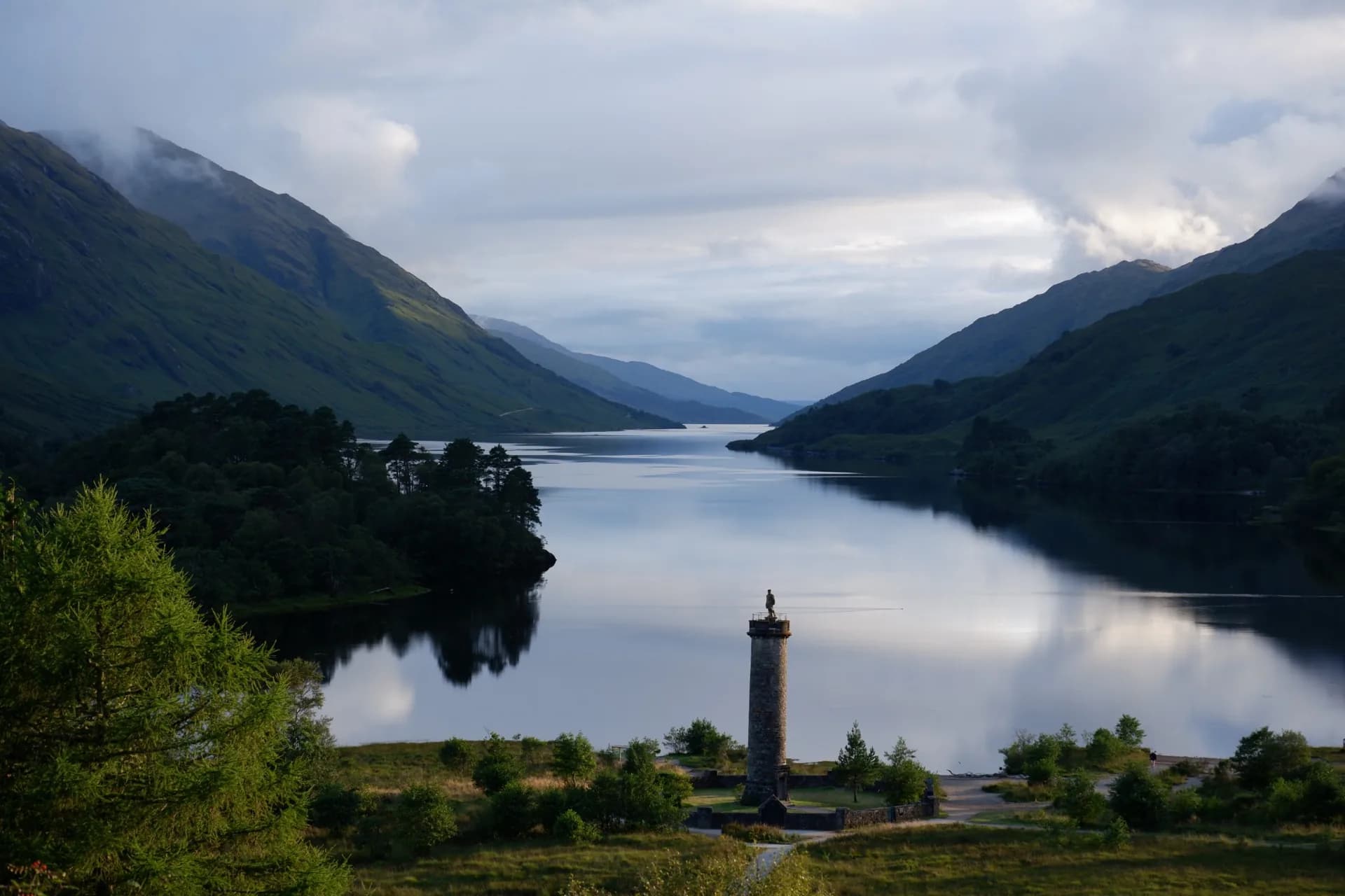 A loch surrounded by mountains beneath a cloudy sky